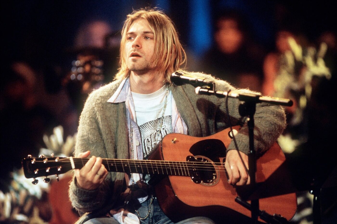 Kurt Cobain wearing his famous green cardigan sweater and playing the most expensive guitar sold at auction, as seen at the MTV Unplugged performance